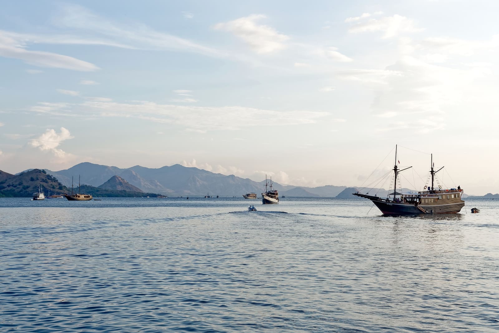 Traditional wooden phinisi boats sailing near Kelor Island